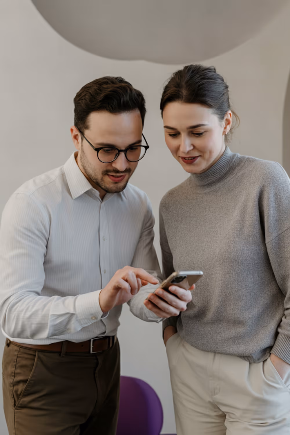 Zwei Personen stehen zusammen und schauen auf ein Smartphone, während der Mann auf den Bildschirm tippt.