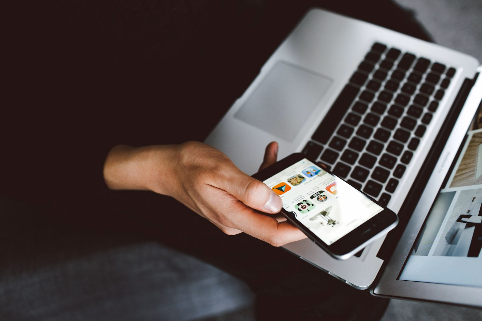 Hände halten ein modernes Smartphone vor einem aufgeklappten Laptop – planbarer Zugang zu aktueller Technik.