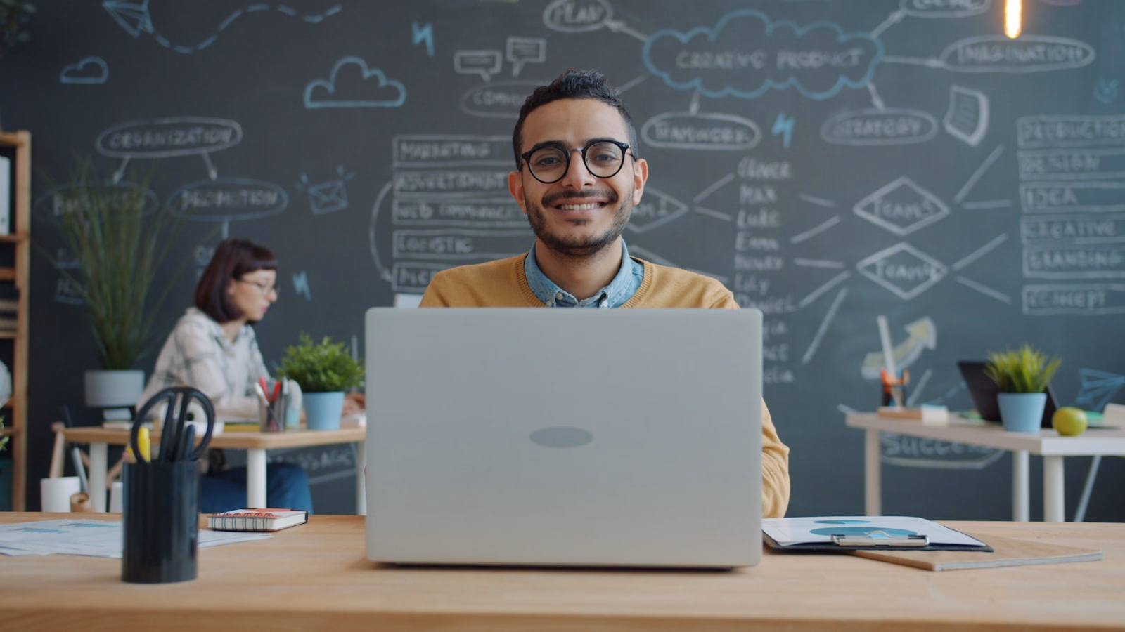 Lächelnde Person an einem aktuellen Laptop im modernen Büro – Sinnbild für den Zugang zu moderner Technik.