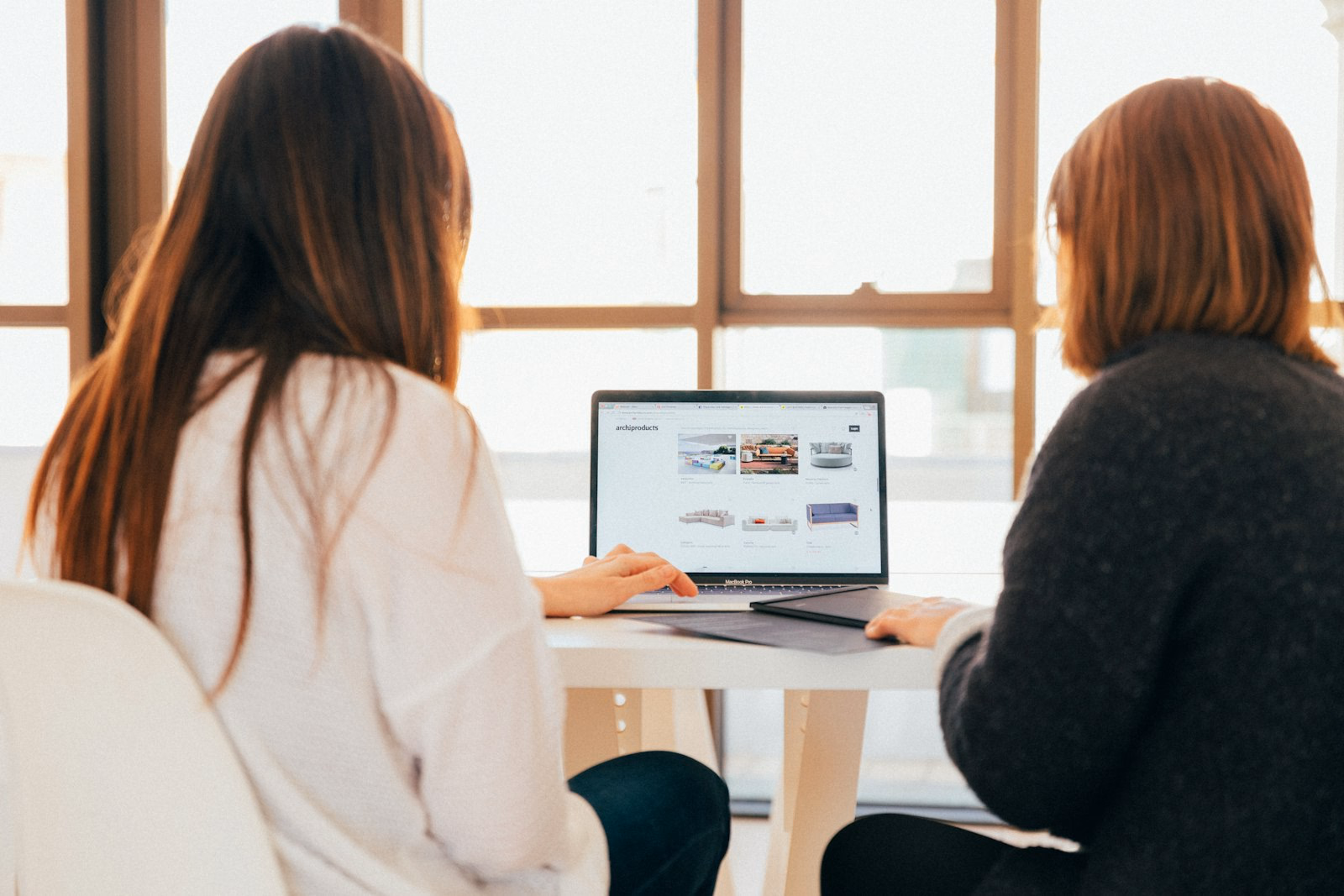 Zwei HR-Kolleginnen besprechen entspannt am Laptop die Verwaltung ihrer Mitarbeiter-Benefits.