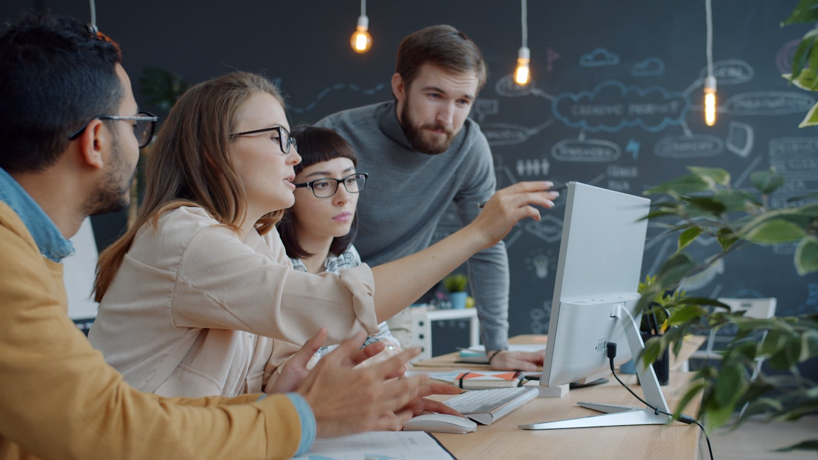 Vier Kolleginnen und Kollegen besprechen am Bildschirm im Büro die IT-Beschaffung ihres Unternehmens.