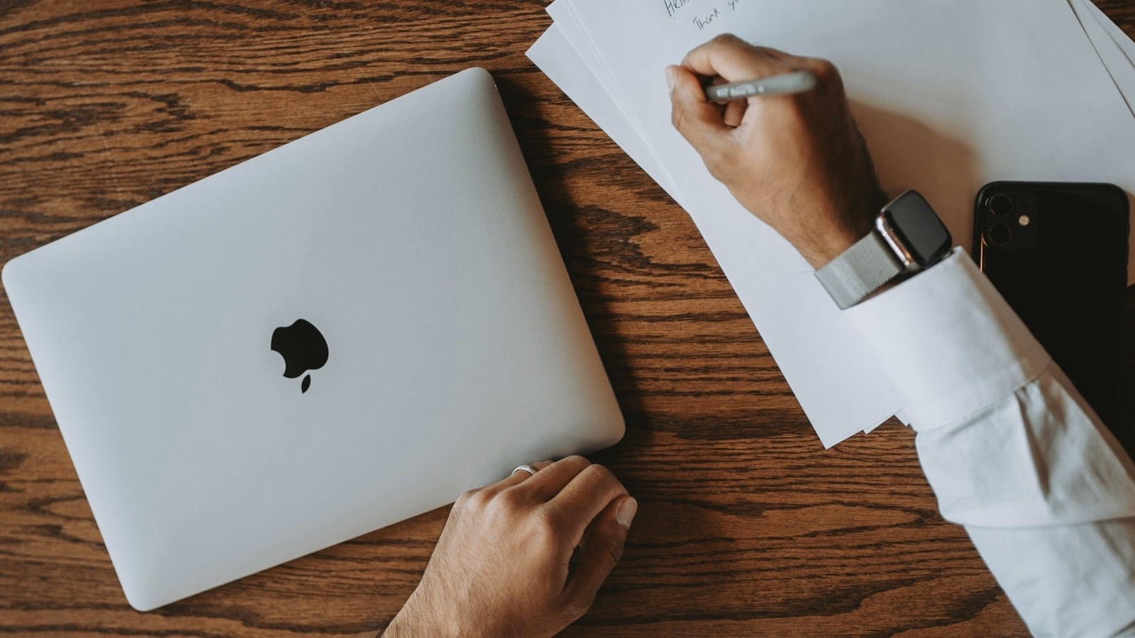 Person unterschreibt ein Dokument neben einem zugeklappten Notebook und einem Smartphone – der Rahmenvertrag als erster Schritt zum Mitarbeiter-PC-Programm.