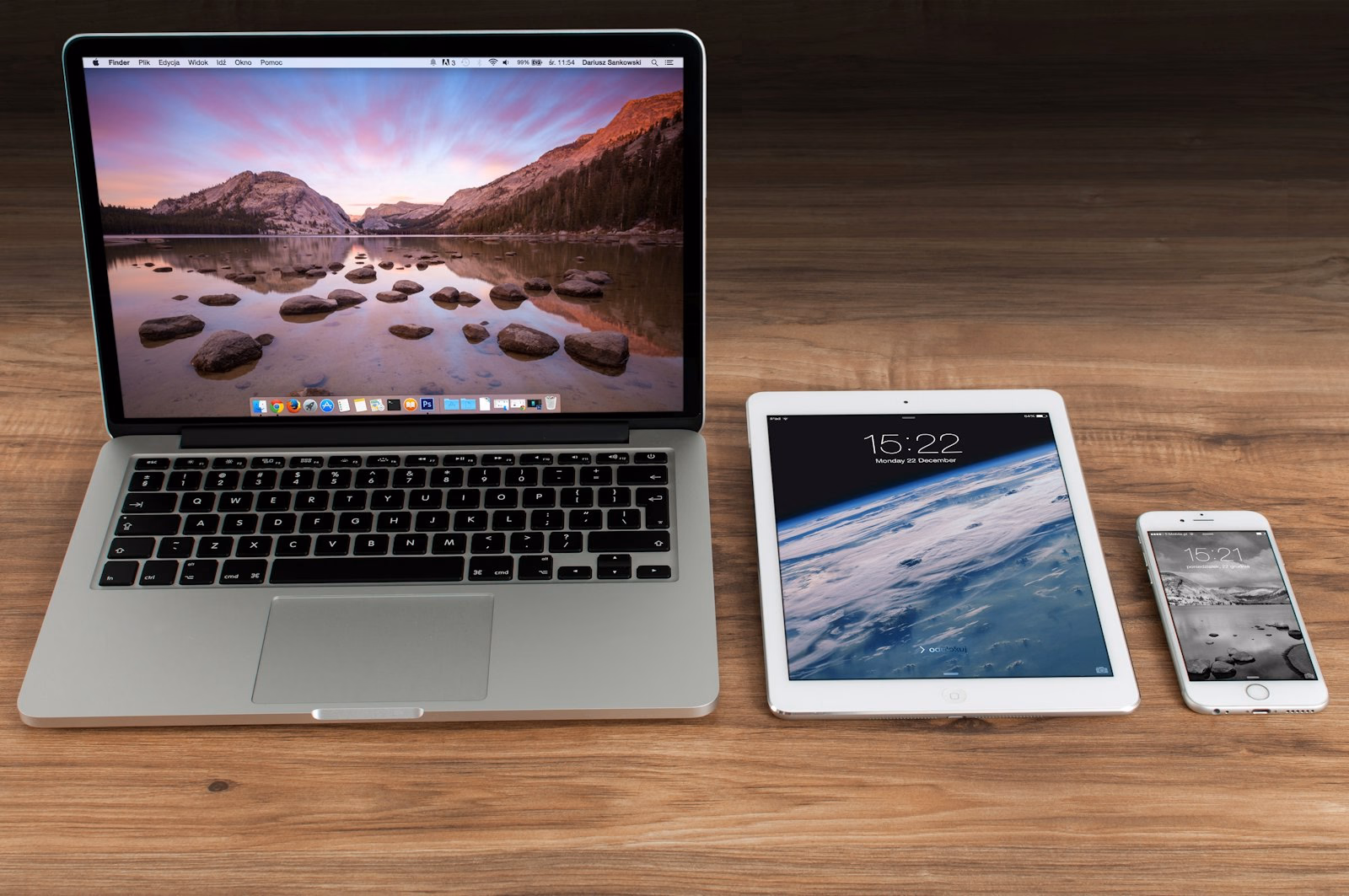 Laptop, Tablet und Smartphone nebeneinander auf einem aufgeräumten Schreibtisch.