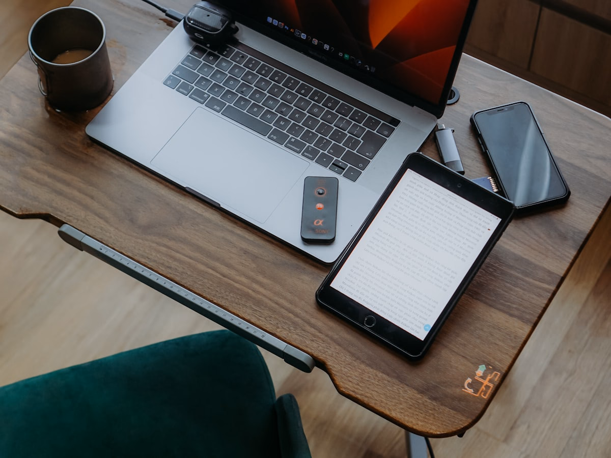 Notebook, Tablet und Smartphone mit Kaffeetasse auf einem Holzschreibtisch – private Wunschtechnik über meinMPP.