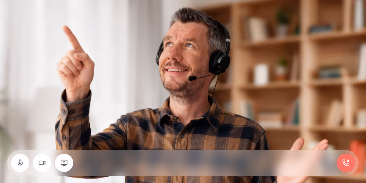Dominik Albers mit Headset und kariertem Hemd lächelt und zeigt während eines Demo-Calls mit virtueller Benutzeroberfläche nach oben links.